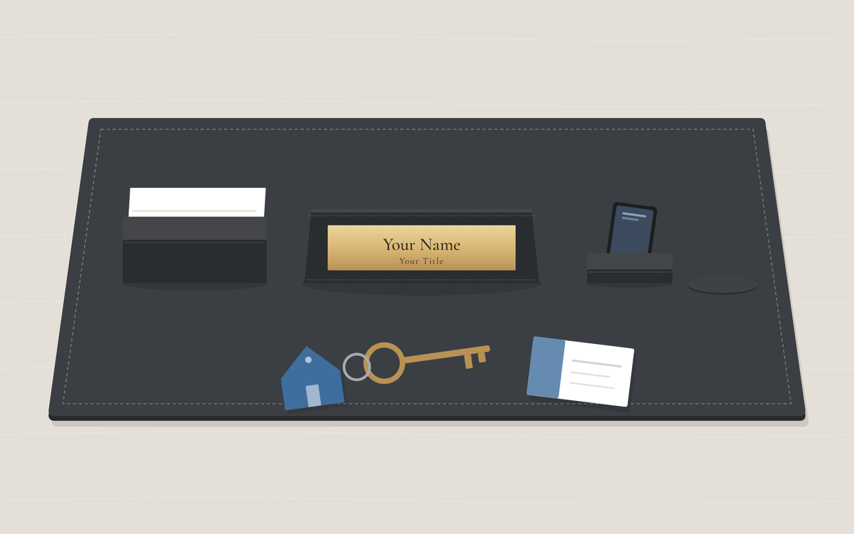 Illustration: a black desk pad with a business card holder, a nameplate and a phone stand, and in front a key on a ring with a house-shaped tag beside a business card